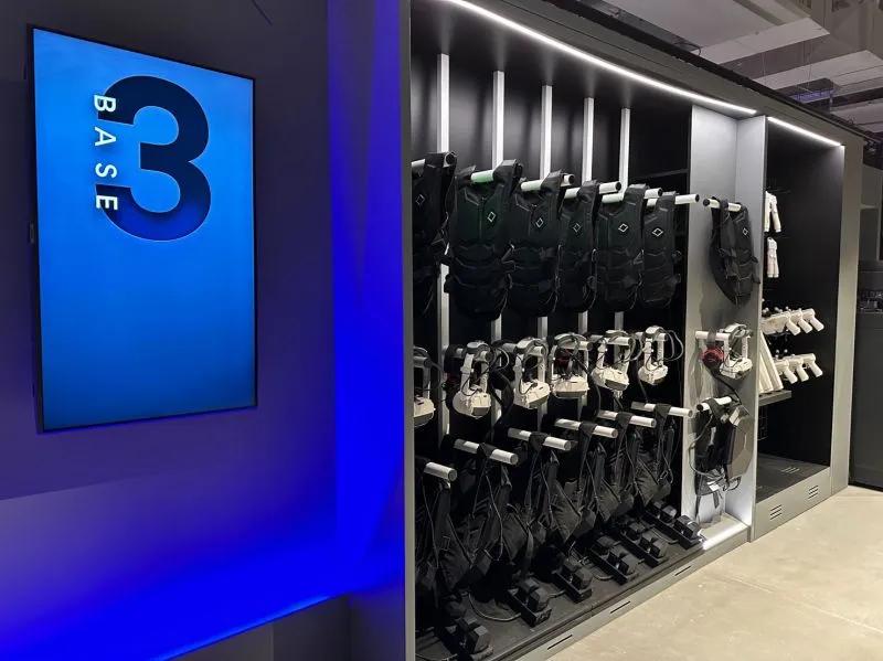 A rack of equipment for a VR experience including vest, headsets and guns