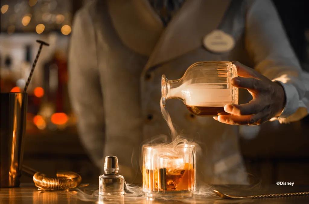 A bartender preparing a smoking, elaborate cocktail at a Disney Hotel bar in Disneyland Paris.