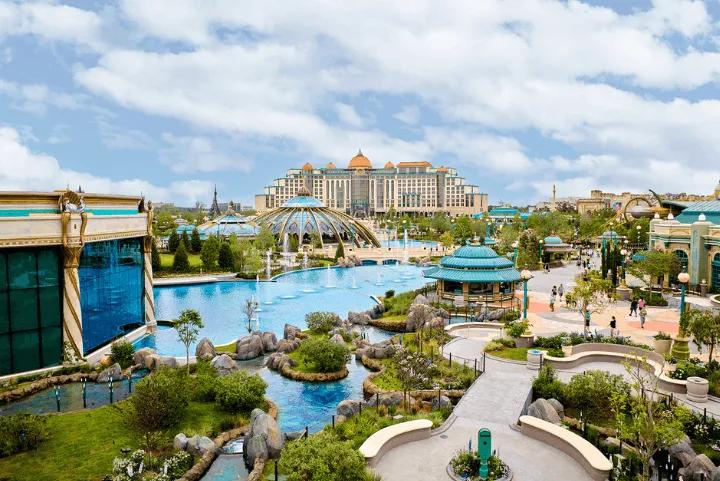 Aerial view of Celestial Park's lagoon and fountains at Epic Universe, with the Helios Grand Hotel in the background