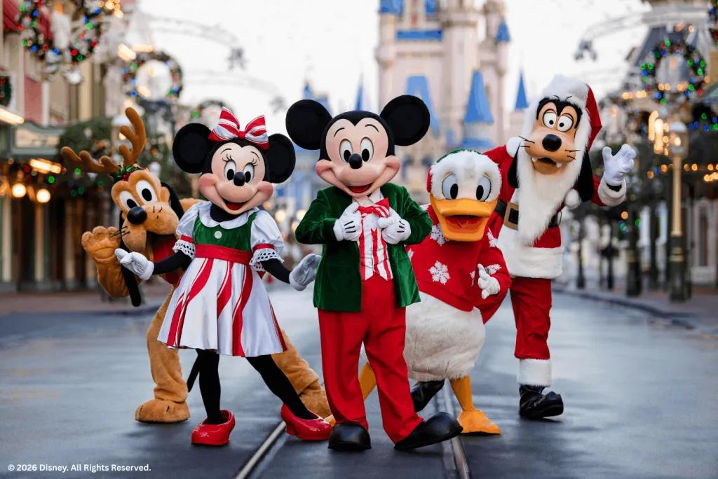 Disney characters in holiday costumes posing on Main Street with Cinderella Castle in the background.