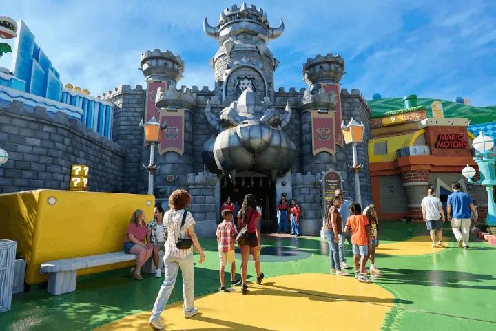 Bowser's castle entrance to Mario Kart: Bowser's Challenge at Super Nintendo World, with visitors walking through the plaza.