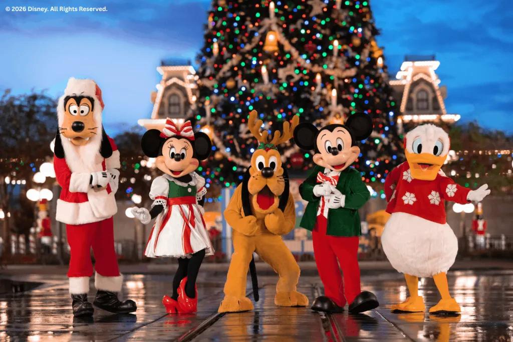 Goofy, Minnie, Pluto, Mickey, and Donald in holiday costumes posing in front of the Christmas tree during Mickey's Very Merry Christmas Party