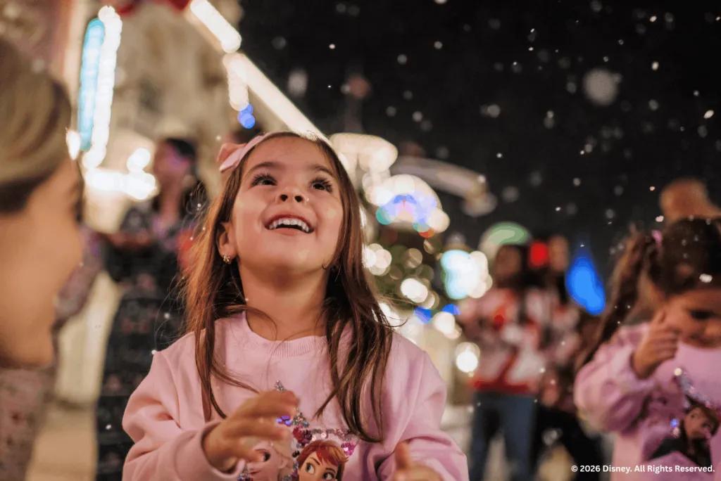 Young girl smiling up at falling snow during Mickey's Very Merry Christmas Party