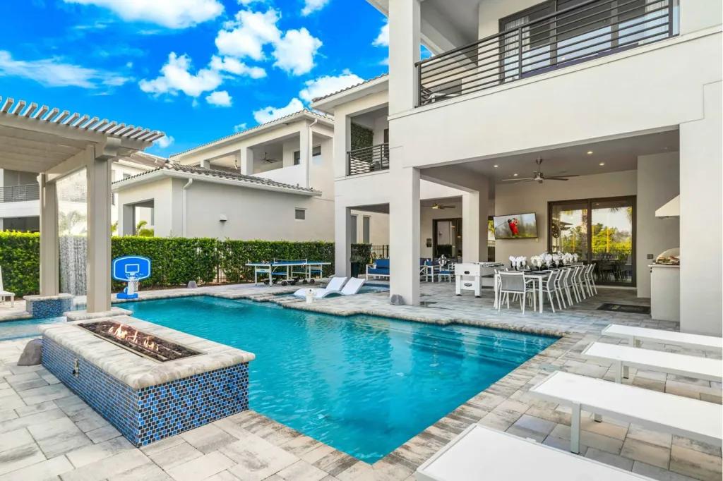 Luxury villa private pool deck at Reunion Resort with a fire pit feature, loungers, and a covered patio entertainment area
