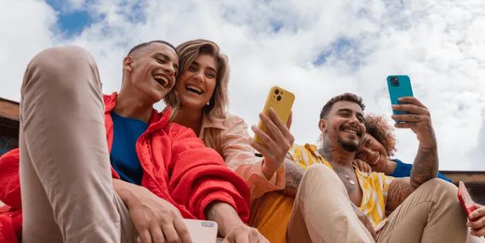 Group of friends using their smartphones while laughing.