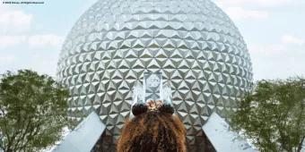 A young girl wearing Minnie ears facing towards Spaceship Earth at EPCOT