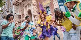 Menschen tanzen mit Mardi Gras Künstlern in bunten, mit Federn geschmückten Kostümen
