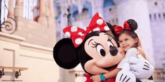 A young girl hugging Minnie Mouse in front of Cinderella Castle at Walt Disney World