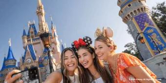 Three guests taking a selfie outside Cinderella Castle