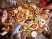 A family dining at a round wooden table covered in food