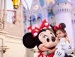 A young girl wearing a blue Magic Band hugging Minnie Mouse in front of Cinderella Castle at Walt Disney World