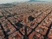 Layout of Barcelona with a view of the Sagrada Familia cathedral. The city is laid out with straight roads and buildings shaped in squares. They all have the same colour scheme with white and orange walls and roofs.