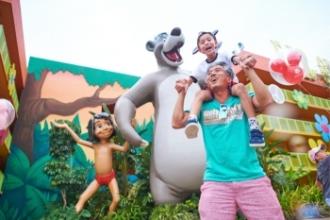 Father and son smiling while next to Jungle Book character statues
