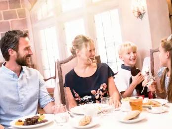 A family with two children sitting at a table eating a meal