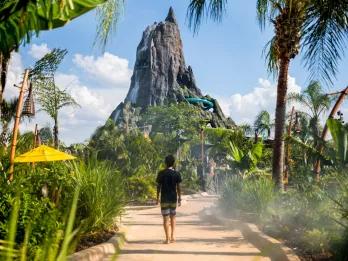 A child in a wetsuit walking along a path lined with plants towards the volcano at Volcano Bay