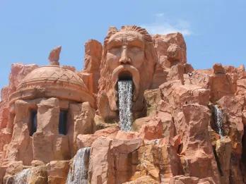 A rock formation carved to look like a face with a waterfall coming out of the open mouth
