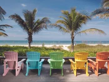 A row of different coloured beach chairs looking out onto the beach