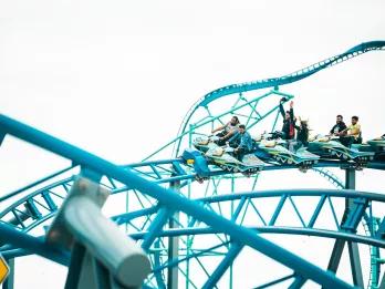 People riding a coaster with ride vehicles shaped like snowmobiles on a blue track