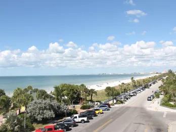 A view down a road running along a white sandy beach and blue ocean