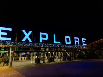 An entrance gate decorated with Christmas decorations and "EXPLORE" lit up with blue lights
