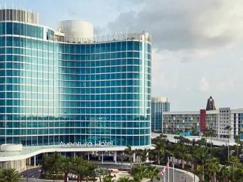 A tall hotel covered in glass panels with a rooftop bar on top