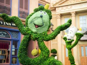 Plant sculpture of the cartoon characters of a grandfather clock with a cartoon face and a candlestick with a cartoon face from Disney's Beauty and the Beast. 