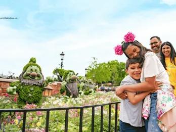 A boy and girl hugging next to topiaries of the seven dwarves from Snow White