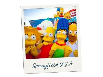 The four characters of the Simpsons, big yellow people cartoon characters include Homer, Marge, Bart and Lisa. They are stood in front of their ride which has giant cartoon clown face as opening. The polaroid is labelled Springfield U.S.A.