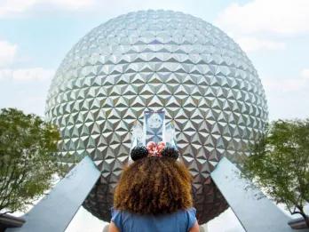 A girl looking up at Spaceship Earth, a large geodesic sphere