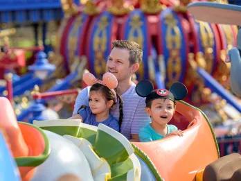 Two children and their father sat in a ride vehicle shaped like Dumbo