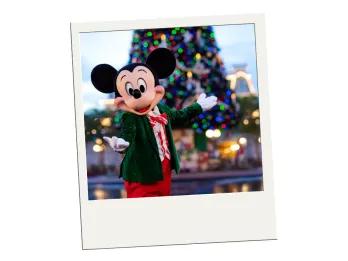 A polaroid of Mickey Mouse in front of a large Christmas tree