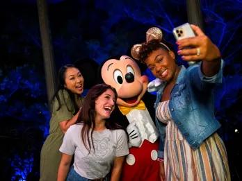 A group of friends taking a selfie with Mickey Mouse