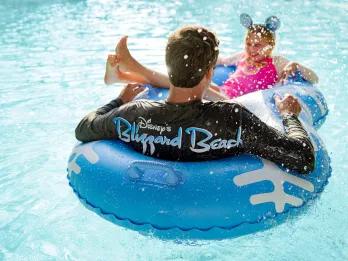 A man and girl sat in a raft in a lazy river at Disney's Blizzard beach