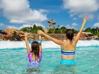 A mother and daughter waiting for a wave to hit them in a water park wave pool