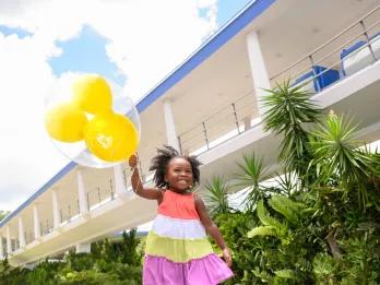 A young girl holding a balloon in front of the Tomorrowland PeopleMover