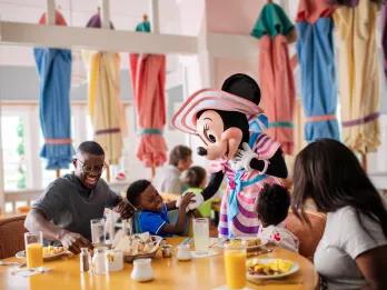 A family eating breakfast while meeting Minnie Mouse