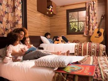 A family sitting on a hotel room bed reading a book