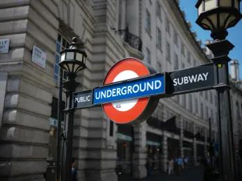Red circle with blue line through it and white block writing saying UNDERGROUND sign. There are old lamp posts on either side.