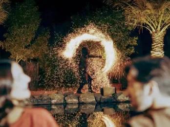 Couple watching a fire dancer perform at a desert camp at night