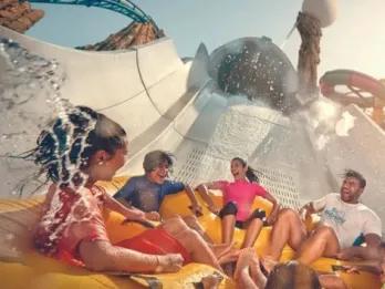 Four people laughing on a water slide at Yas Waterworld.