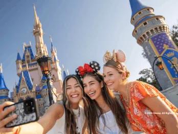 Three guests taking a selfie outside Cinderella Castle