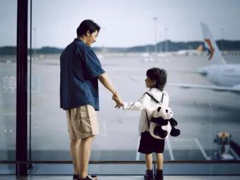 A father and son looking out the window at an airport