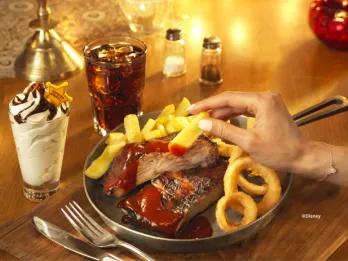 A hearty BBQ meal at The Lucky Nugget Saloon at Disneyland Paris, featuring grilled ribs with barbecue sauce, chunky chips and onion rings, served with a cola and a chocolate sundae