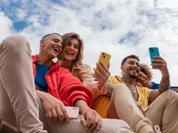 Group of friends using their smartphones while laughing.
