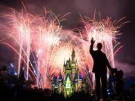 Cinderella Castle lit up with fireworks in the background and a statue of Walt and Mickey in the foreground
