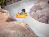 A young girl on a raft going down a water slide