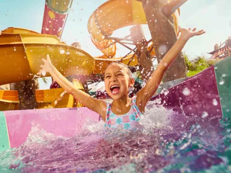 Happy child having fun with arms raised on a water attraction at Yas Waterworld Abu Dhabi