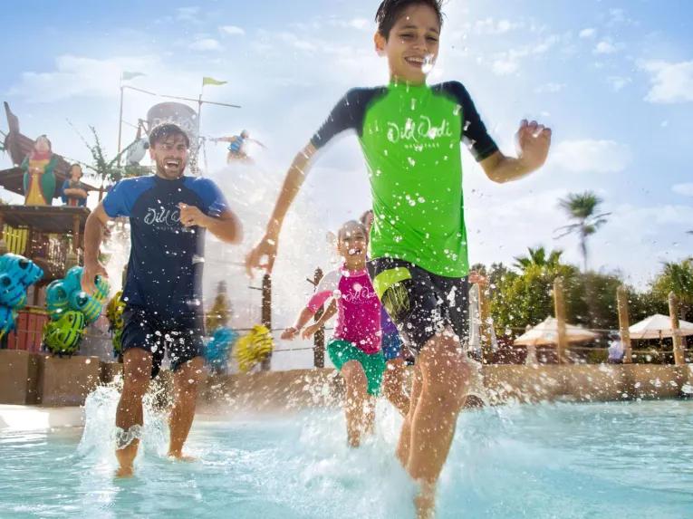 People running through water and smiling at Wild Wadi Waterpark