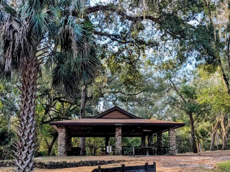 A stone pillar park pavilion surrounded by oak and palm trees on the Rock Springs River Tubing & Apopka Wildlife Adventure tour.