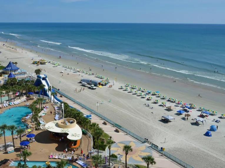 Aerial view of beachfront resort pools alongside the wide shoreline of Daytona Beach.